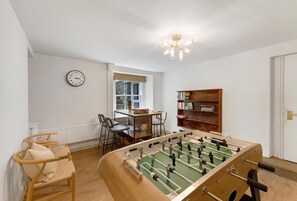 Ein Zimmer mit Tischfußballtisch, Bücherregal, Uhr und Fenster mit Aussicht.