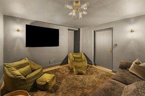 A room with a flat-screen TV mounted on the wall, a door, and two bean bag chairs. - 4 Bed in Windermere (oc-lr186) (Windermere)