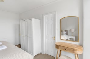 A bedroom with a bed, a wardrobe, a vanity with a mirror, and a bedside table. - 4 Bed in Windermere (oc-lr186) (Windermere)