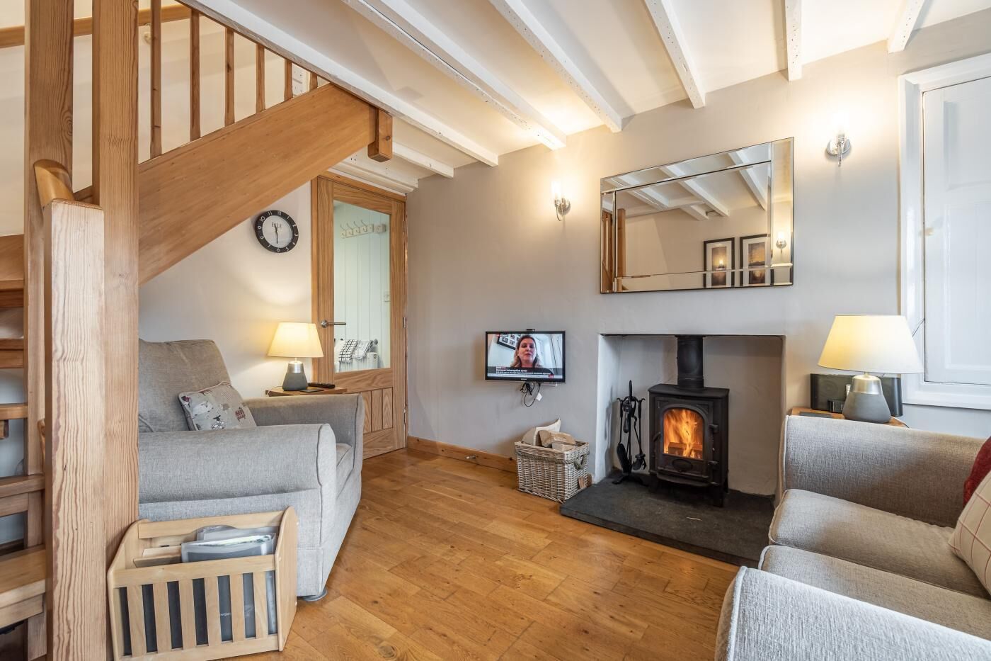 A cozy living room with a fireplace, wooden staircase, and a television.
