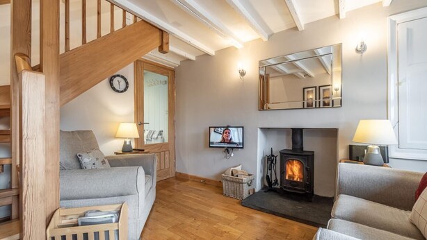 Un salon chaleureux avec une cheminée, un escalier en bois et un téléviseur.