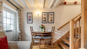 Un coin repas avec une table et des chaises en bois, un vase rempli de fleurs et des tableaux encadrés accrochés au mur.