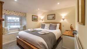 Une chambre à coucher comprenant un lit, des tables de chevet, une fenêtre avec des stores et des lampes fixées au mur.