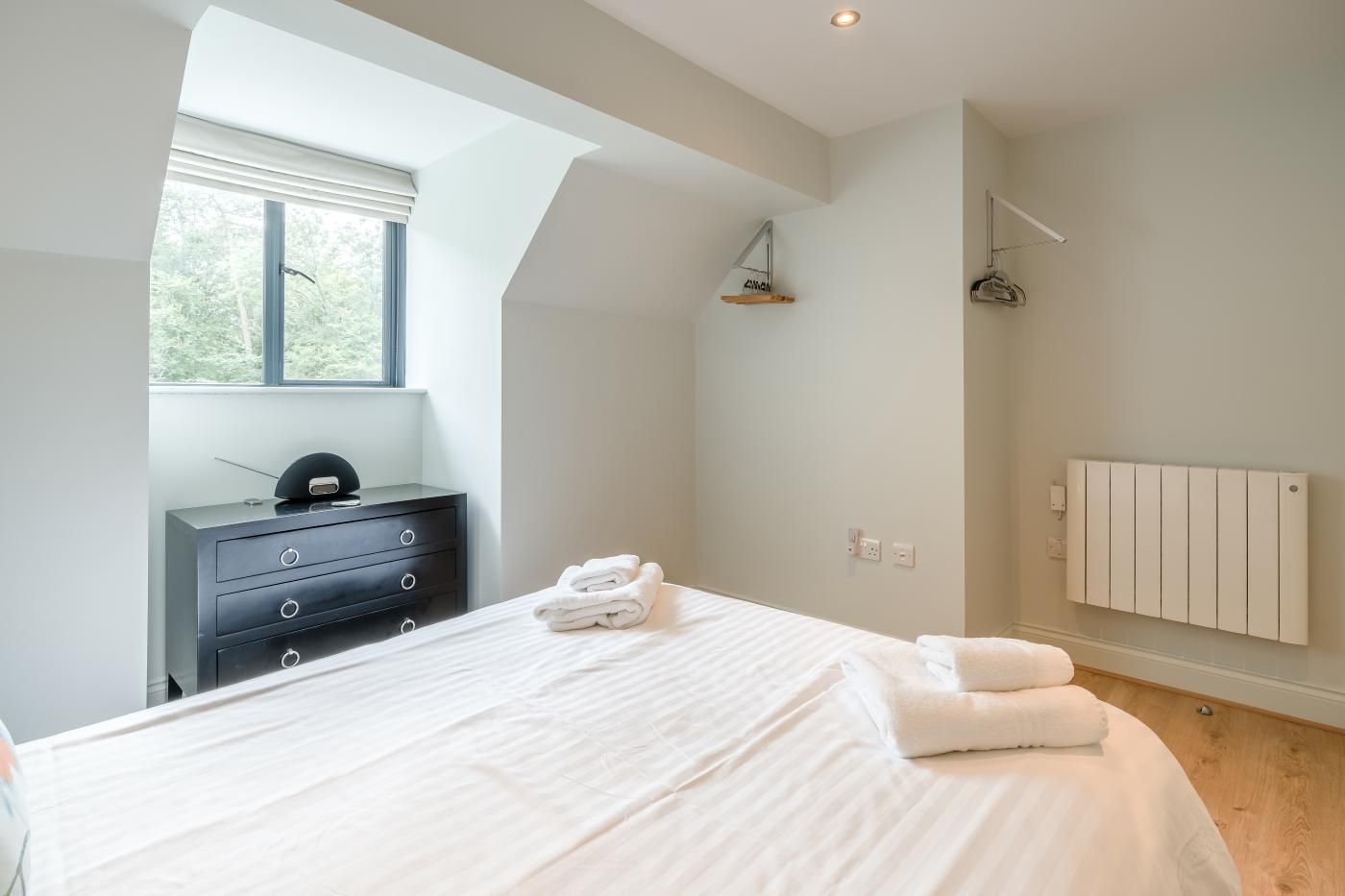 A bedroom with a bed, a dresser, a radiator, and a window with blinds.