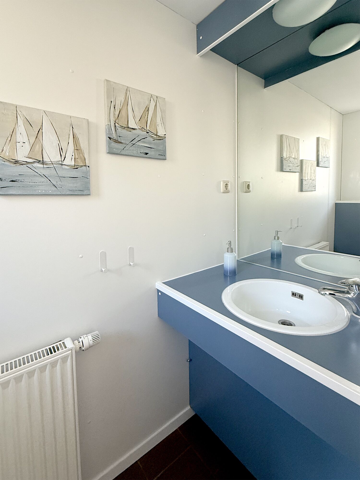 Un bagno con due lavandini, uno specchio e opere d'arte appese al muro.