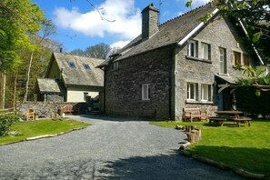 A stone building with a gravel driveway, wooden benches, and a picnic table. - 2 Bed in Ambleside (oc-lr217) (Claife)
