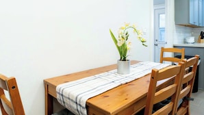 A wooden dining table with a plaid tablecloth, a potted plant, and cushioned chairs. - Foothills LA Family Friendly House (Glendora)