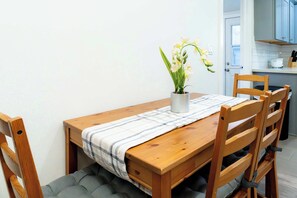 A wooden dining table with a plaid tablecloth, a potted plant, and cushioned chairs. - Foothills LA Family Friendly House (Glendora)