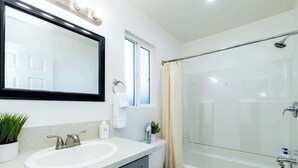 A modern bathroom with a white sink, mirror, and bathtub. - Foothills LA Family Friendly House (Glendora)