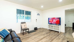 A living room with a leather sofa, a television, and a wooden floor. - Foothills LA Family Friendly House (Glendora)