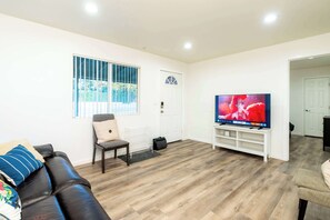 A living room with a leather sofa, a television, and a wooden floor. - Foothills LA Family Friendly House (Glendora)
