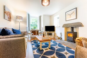Ein gemütliches Wohnzimmer mit einer Couch, einem Couchtisch, einem Kamin und einem Fernseher.