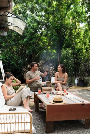 A group of people sitting at an outdoor table with a drink, surrounded by greenery. - Modern Cozy Stay w Outdoor Patio & Grill (Pomona)