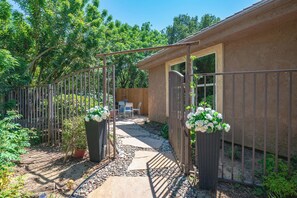 A patio area with a stone pathway, metal gate, and potted plants. - Modern Cozy Stay w Outdoor Patio & Grill (Pomona)