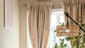 Une chambre à coucher avec un lit, des rideaux beiges, une fenêtre et un appareil de climatisation.