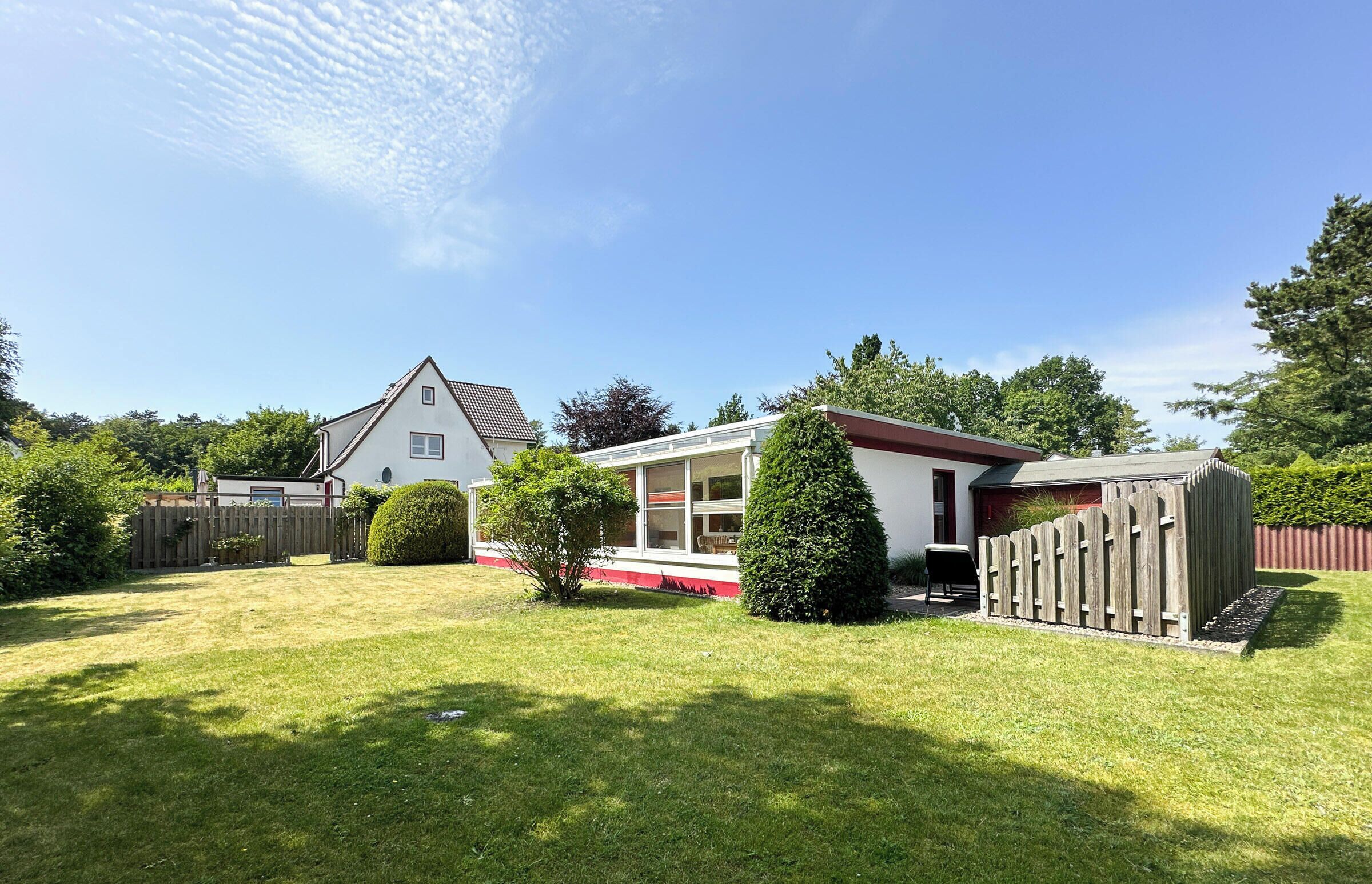 Ein Wohnhaus mit gepflegtem Rasen, einem Holzzaun und einem kleinen Gartenhaus.
