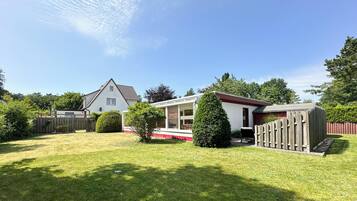 Ein Wohnhaus mit gepflegtem Rasen, einem Holzzaun und einem kleinen Gartenhaus.