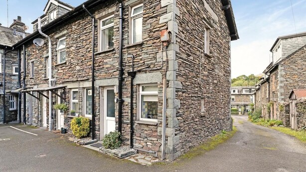 A stone building with multiple windows, a porch, and a paved driveway. - 2 Bed in Ambleside (oc-lr141) (Ambleside)