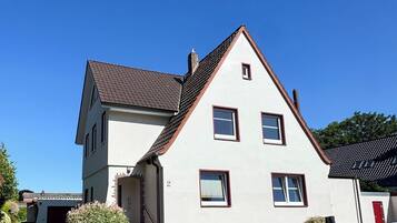 Ein zweistöckiges Haus mit steiler Satteldach und Ziegelkeller, sowie einer Garage.