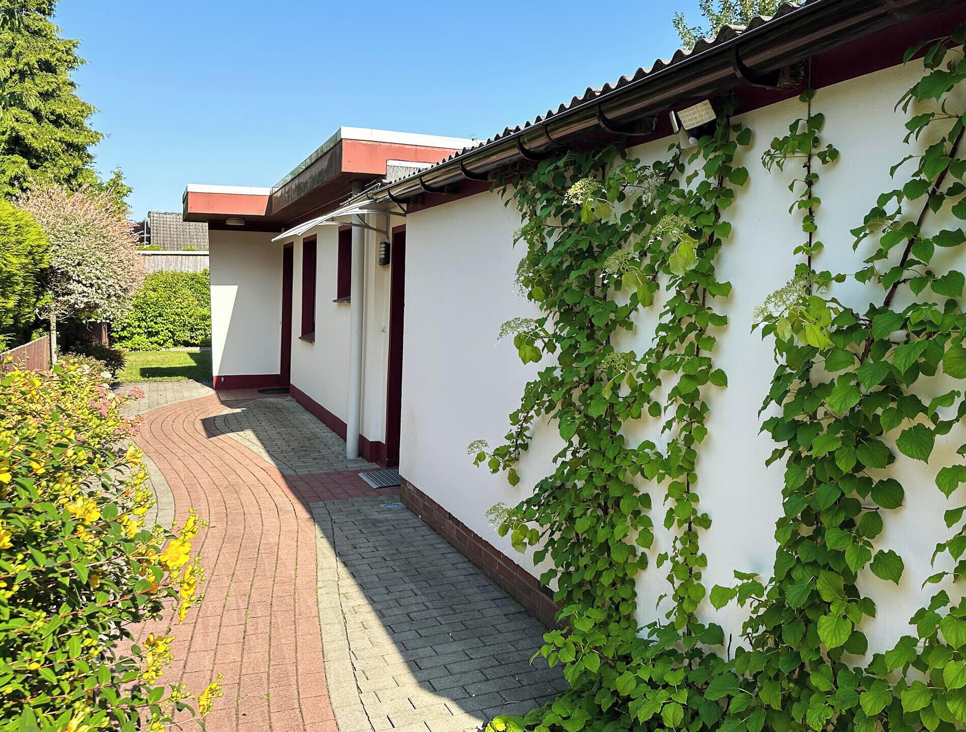 Ein schmaler Weg, der zu einem Gebäude mit weißer Fassade und rotem Dach führt.