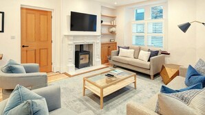 Una sala de estar con chimenea, sofá, mesa de centro y televisor.