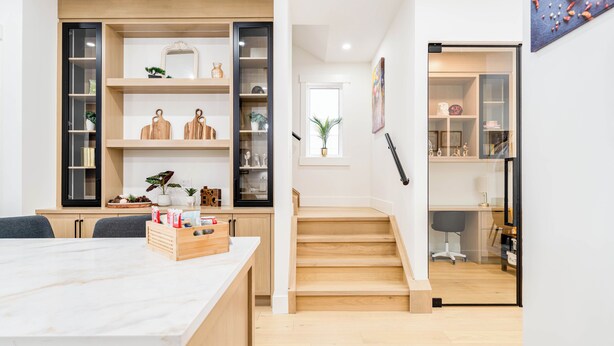 A modern kitchen with wooden cabinets, a marble countertop, and a dining area with a table and chairs. - Stampede Last Minute Deal 3BR Home Downtown Patio & AC (Calgary)