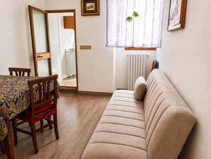 A room with a dining table, a sofa, a mirror, and a radiator. - Domus Clesia (Ostuni)
