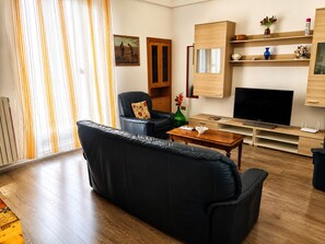 A living room with a black leather sofa, a wooden coffee table, a TV, and a wooden cabinet. - Domus Clesia (Ostuni)