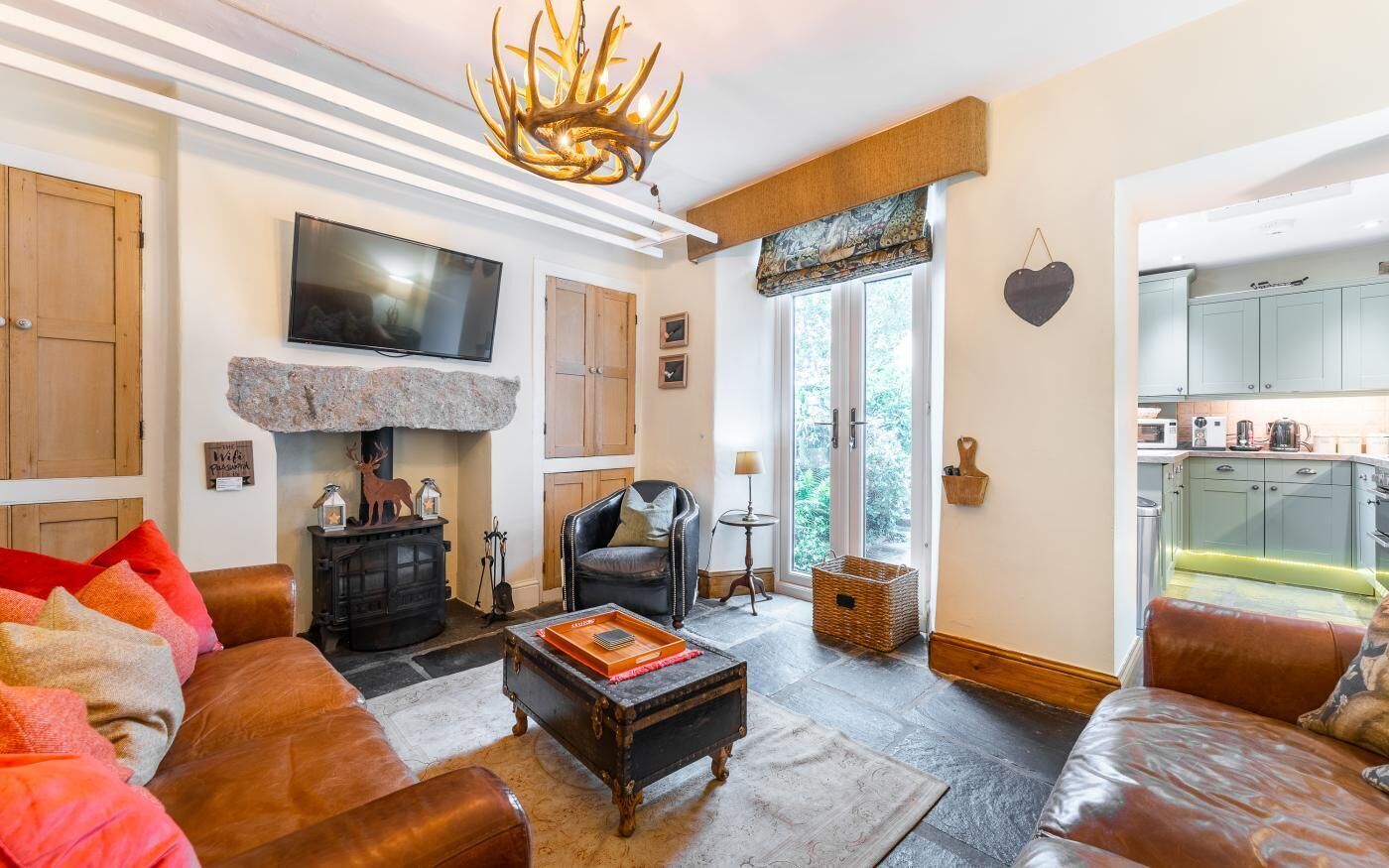 A living room with a fireplace, a television, and a kitchen visible through an open door.