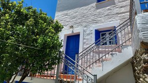 A building with a white exterior, blue doors, and a staircase with metal railings.