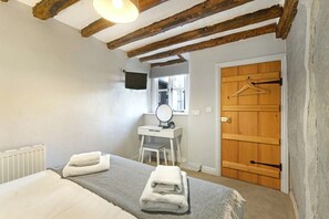 A bedroom with a bed, a bedside table, a mirror, a wooden door, and a radiator. - 2 Bed in Hawkshead (oc-lr062) (Hawkshead)