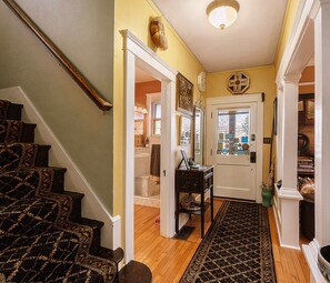 A staircase leading to a room with a wooden floor, a door with a window, and a small table with a lamp. - Burnt Toast Inn and Washington House (Ann Arbor)
