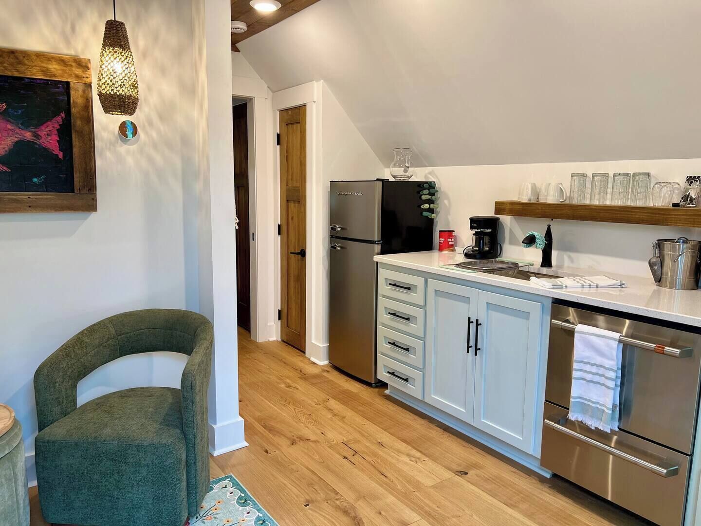 Une cuisine moderne avec des meubles blancs, des appareils en acier inoxydable et un plancher en bois.