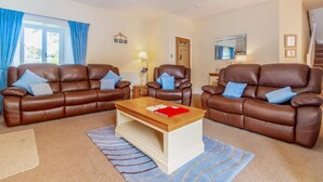 A living room with two brown leather sofas, a wooden coffee table, and a TV. - 3 Bed in Ambleside (oc-lr214) (Claife)