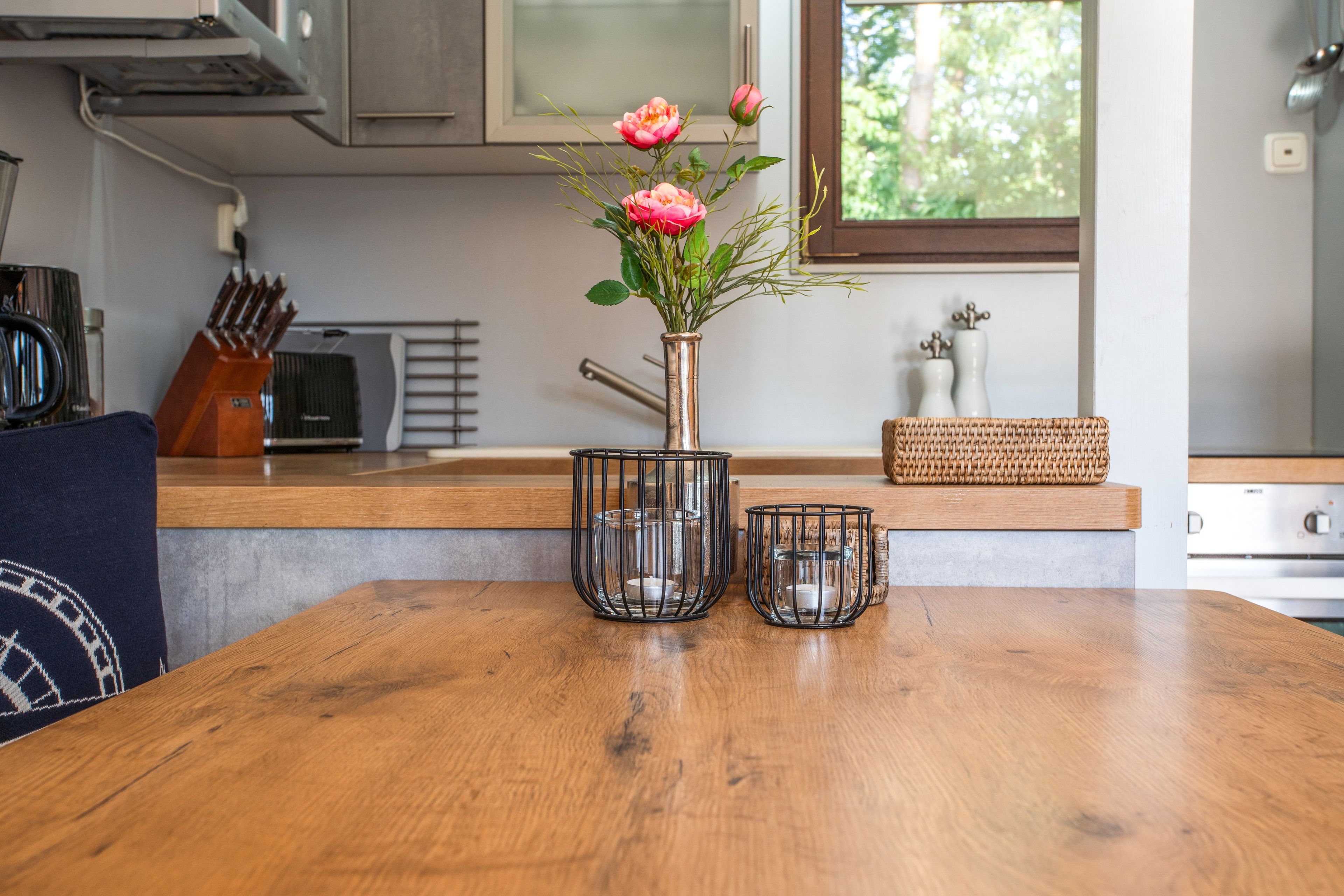 Eine Holzausziehtheke mit einer Blumenvase, zwei Kerzenhaltern und einem gewebten Korb.