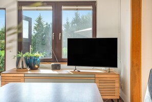 Une pièce avec un bureau en bois, une télévision, une radio et deux plantes en pot.