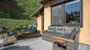 Ein Sitzbereich im Freien mit einer Couch, Stühlen und einem Tisch.