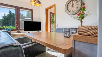 Una sala de estar moderna con una mesa de comedor de madera, un televisor de pantalla plana, un sofá y un reloj de pared.