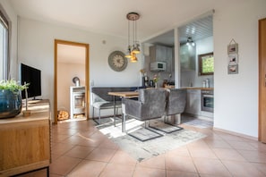 A modern kitchen with a dining area, a built-in oven, and a flat-screen TV. - Bungalow Boddenhaus with Private Terrace, Garden, and Wi-Fi (Sundhagen)