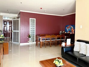 Ein Wohnzimmer mit Essbereich, einem schwarzen Sofa, einem Holztisch und einem Bild an der Wand.