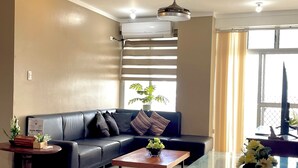 A modern living room with a black leather sofa, a glass coffee table, and a potted plant. - 2-bedroom condo unit in Cebu City (Cebu City)