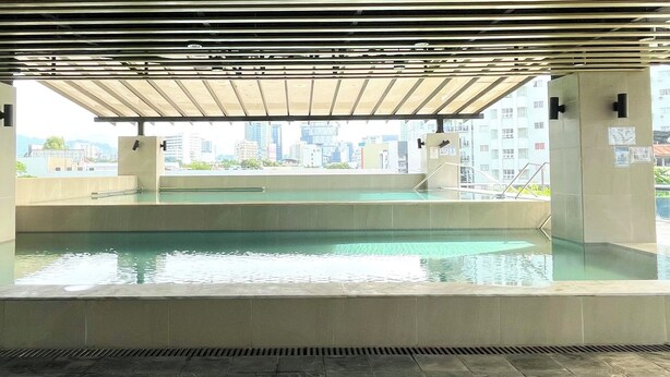 An indoor swimming pool with a view of a cityscape, surrounded by a covered area with railings. - 2-bedroom condo unit in Cebu City (Cebu City)