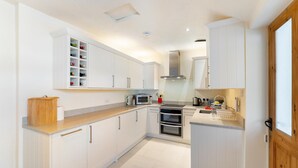 Eine moderne Küche mit weißen Schränken, einer Mikrowelle, einem Backofen und einer Holz Arbeitsplatte.