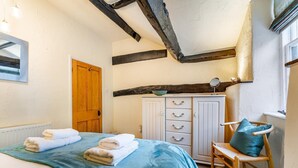Ein Schlafzimmer mit einem Bett, einem Holzschrank, einem Stuhl und einem Fenster.