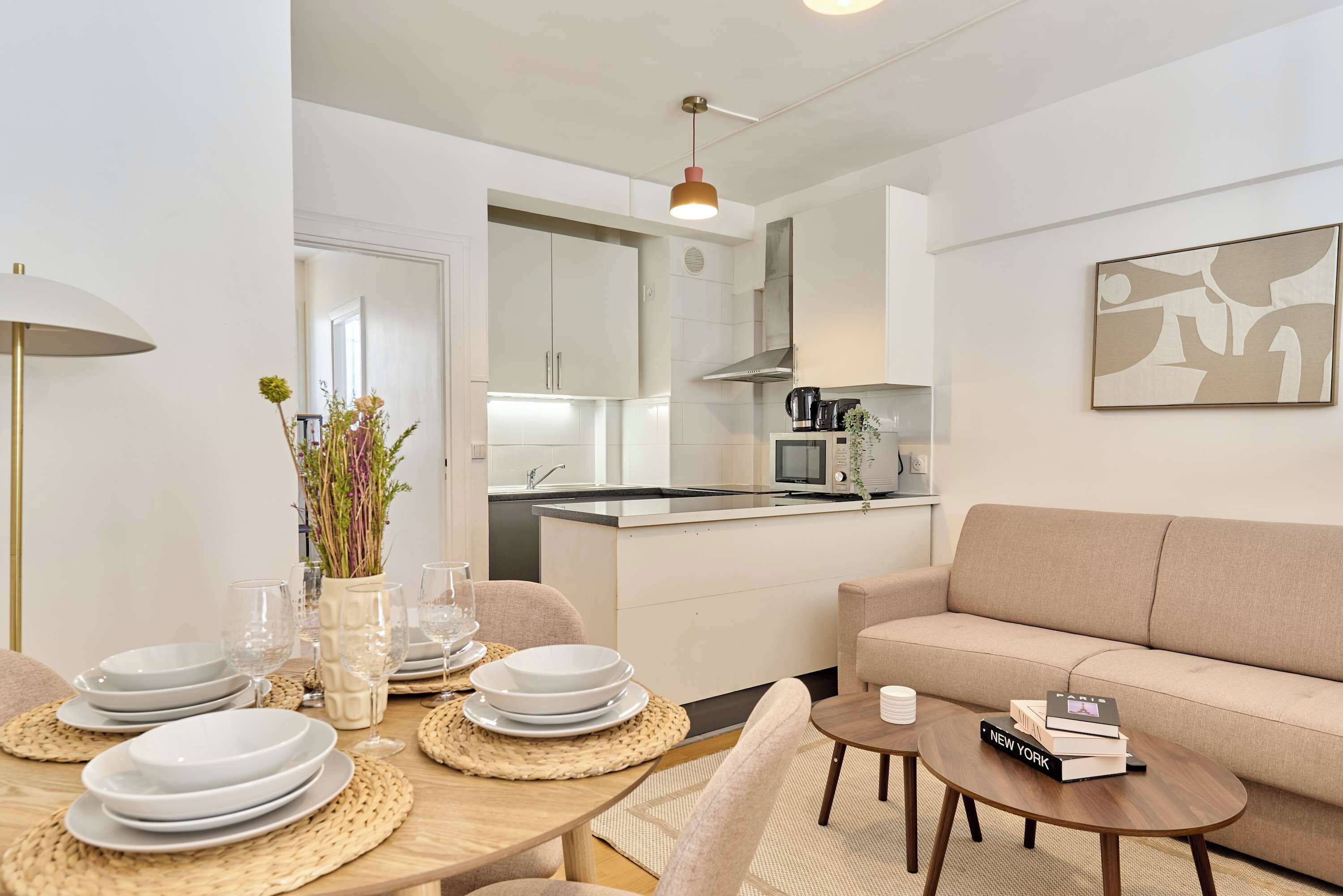 A modern kitchen with white cabinets, a central island, and a dining area with a table set for four.