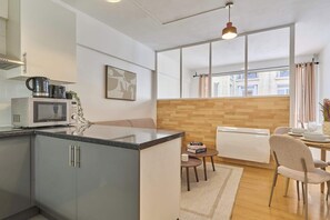 Une cuisine moderne équipée d’un four à micro-ondes, d’une bouilloire et d’un petit coin repas avec une table et des chaises.