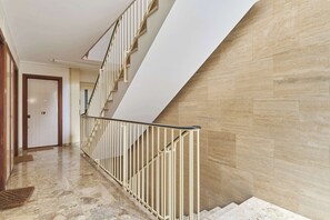 A modern interior with a marble staircase, a wooden door, and a beige wall. - Suite for 4- Arc de Triomphe Faubourg Saint-Honoré (Paris)