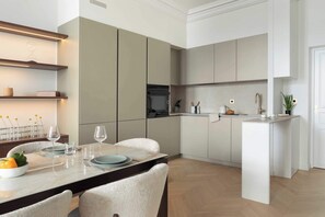 A modern kitchen with a dining area, featuring a marble countertop, white cabinets, and a built-in oven. - Luxurious Apartment 1Bdr Saint Germain des Prés (Paris)