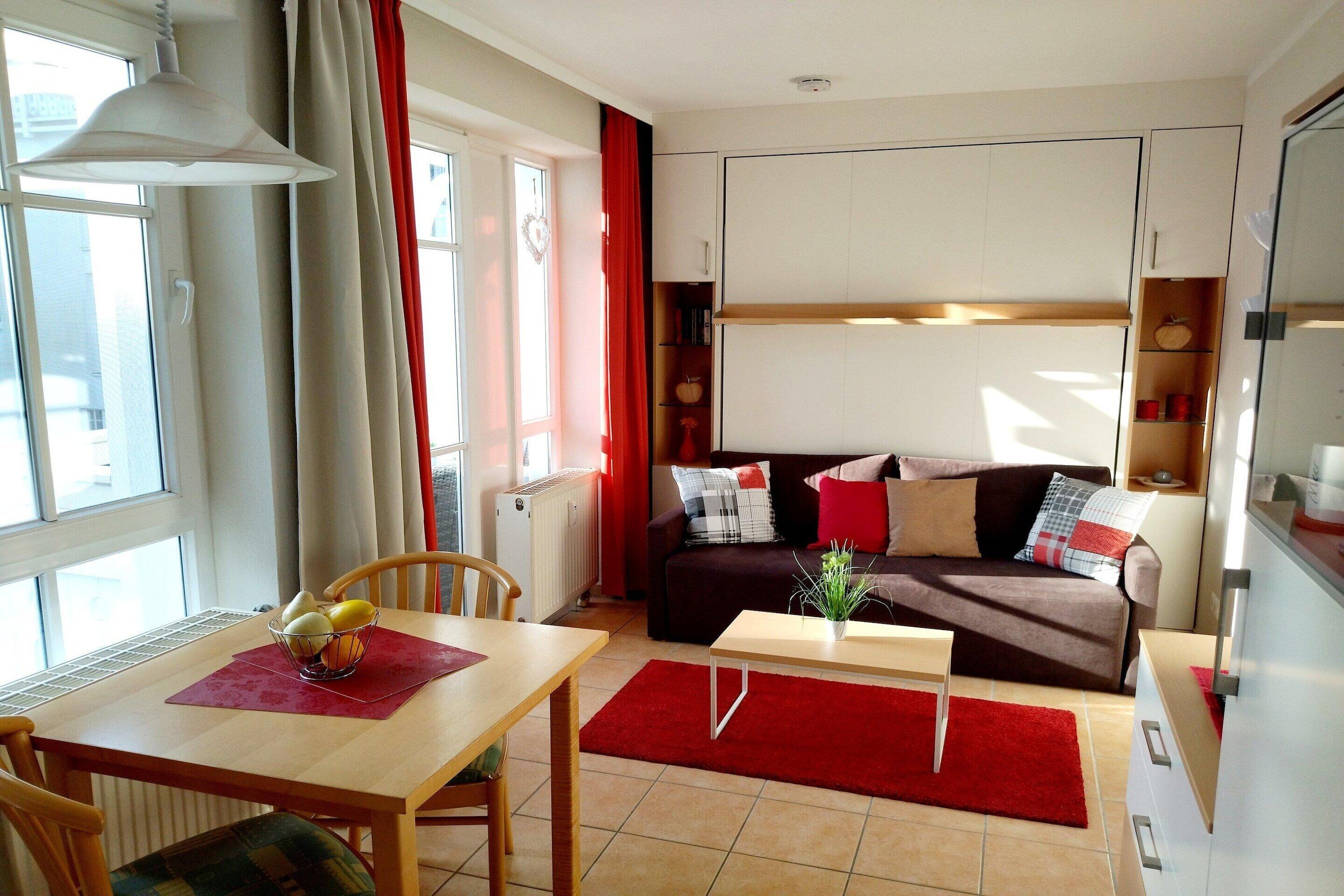 A modern living room with a dining area, a sofa set, and a kitchen area.