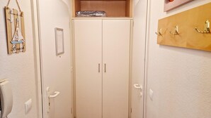 A narrow hallway with a wooden shelf at the top, a coat rack on the right, and a door with a handle on the left. - Charmante Ferienwohnung in Sellin mit Balkon (Sellin)